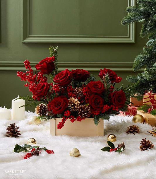 Deep red roses and berries in wooden box with pinecones, festive Christmas floral arrangement