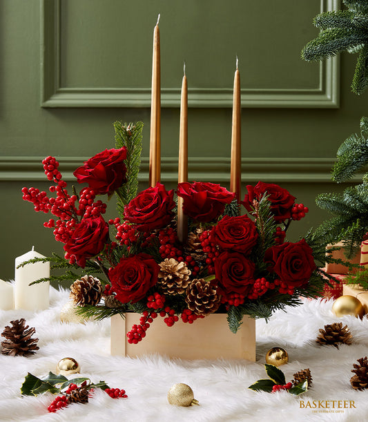 Golden candle Christmas centerpiece with deep red roses, pinecones, and gold taper candles in wooden box