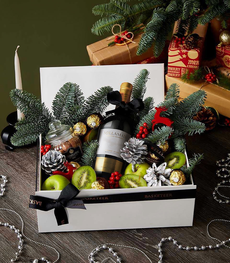 Premium red wine gift box with chocolates, berries, and festive greenery for Christmas