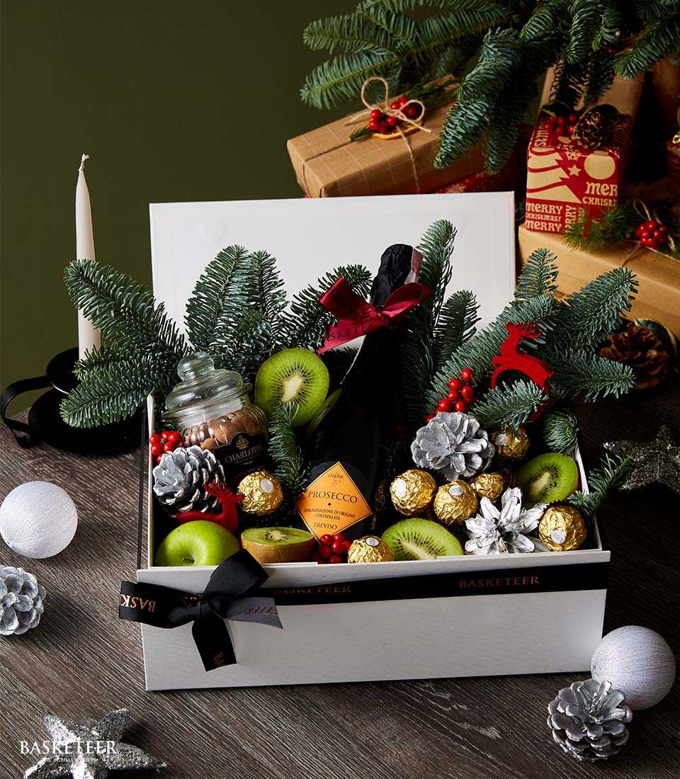 Prosecco Christmas gift box with fresh fruits, gold chocolates, and festive pine greenery