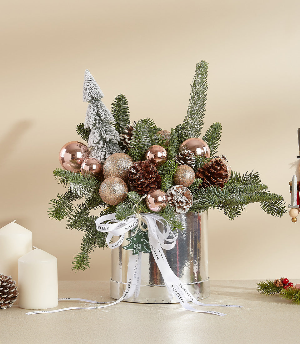 Premium Christmas floral arrangement with roses, evergreens, and gold ornaments in silver cylinder