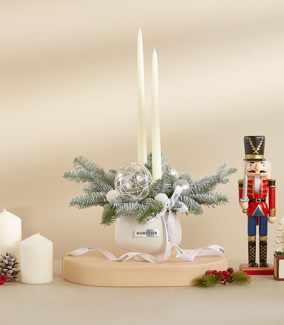 Winter white ceramic vase with cream taper candles, frosted pine, and silver baubles Christmas centerpiece