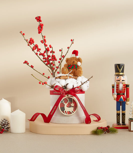 Festive Christmas floral arrangement with white roses, red berries, cinnamon, teddy bear and wooden reindeer ornament