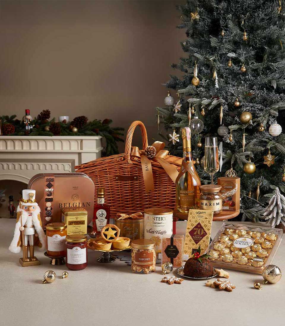 Luxury Christmas hamper with wicker basket, champagne, Belgian chocolates, preserves, and gourmet treats on festive backdrop