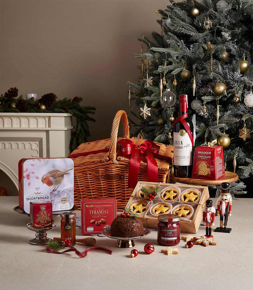 Luxury Christmas wine hamper with red wine, shortbread, honey, chocolate, and festive gourmet treats in woven wicker basket
