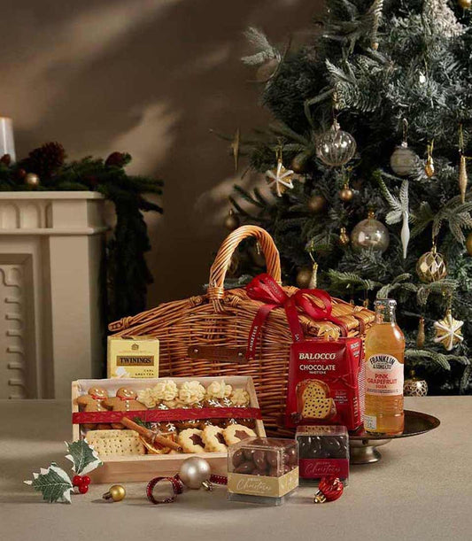Woven wicker Christmas hamper with red ribbon, gourmet treats, tea, cookies, and chocolate-covered nuts