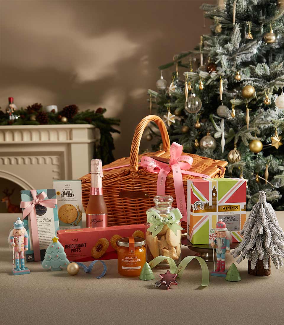 Festive Charm wicker gift basket with pink sparkling wine, Scottish oatcakes, chocolate, marmalade, and tea surrounded by