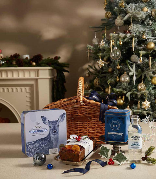 Wicker gift basket with Scottish shortbread, fruitcake, and festive spirits for Christmas