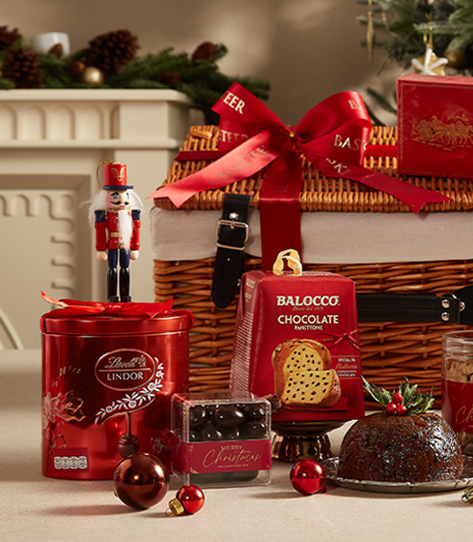 Festive red Christmas hamper with red wines, Lindor chocolates, panettone, and holiday decorations tied with ribbon