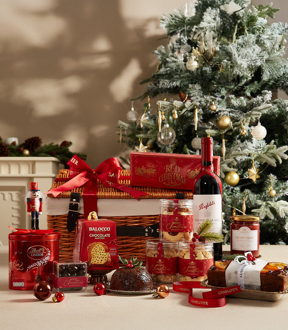 Festive red wicker Christmas hamper with red wine, Panettone, chocolates, tea, and gourmet treats