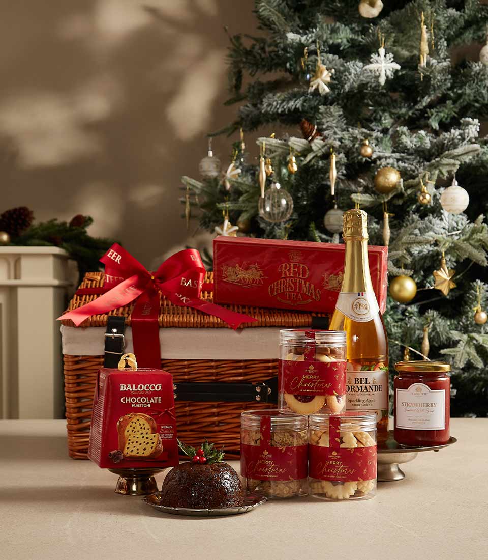 Luxury Christmas hamper with woven wicker basket, festive treats, panettone, pudding, and artisan cookies on festive display