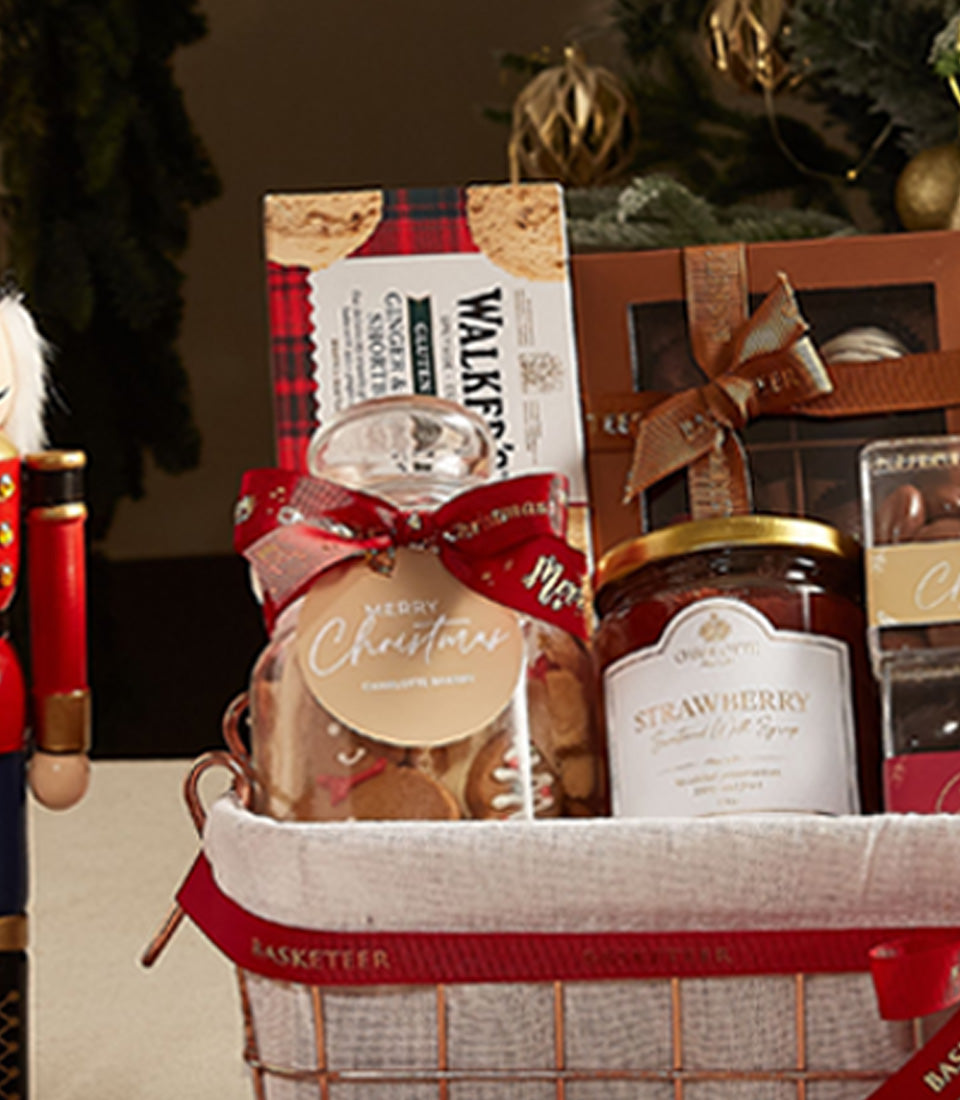 Luxury Christmas wine gift basket with gourmet treats, shortbread, gingerbread cookies, and festive decorations in woven