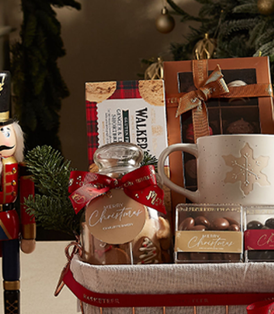 Festive Christmas gift basket with wine, gingerbread cookies, chocolate treats, and gold snowflake mug