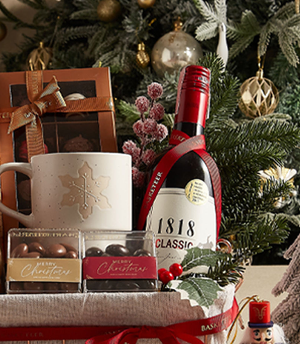 Festive red wine gift basket with gold snowflake mug, chocolates, and Christmas treats
