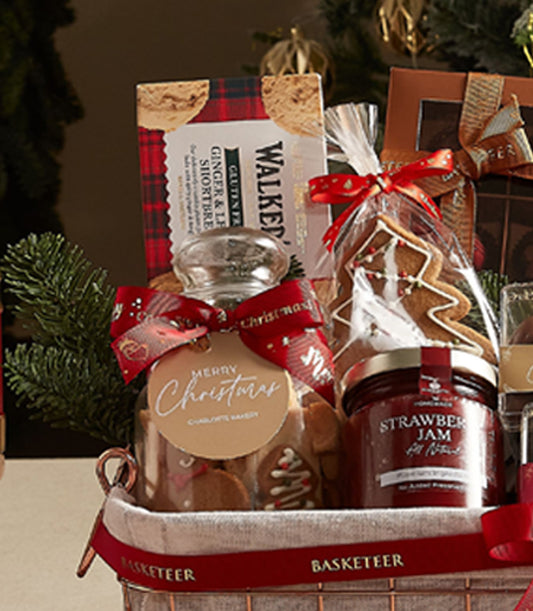 Deluxe Christmas treats basket with gingerbread cookies, strawberry jam, shortbread, and festive red ribbon