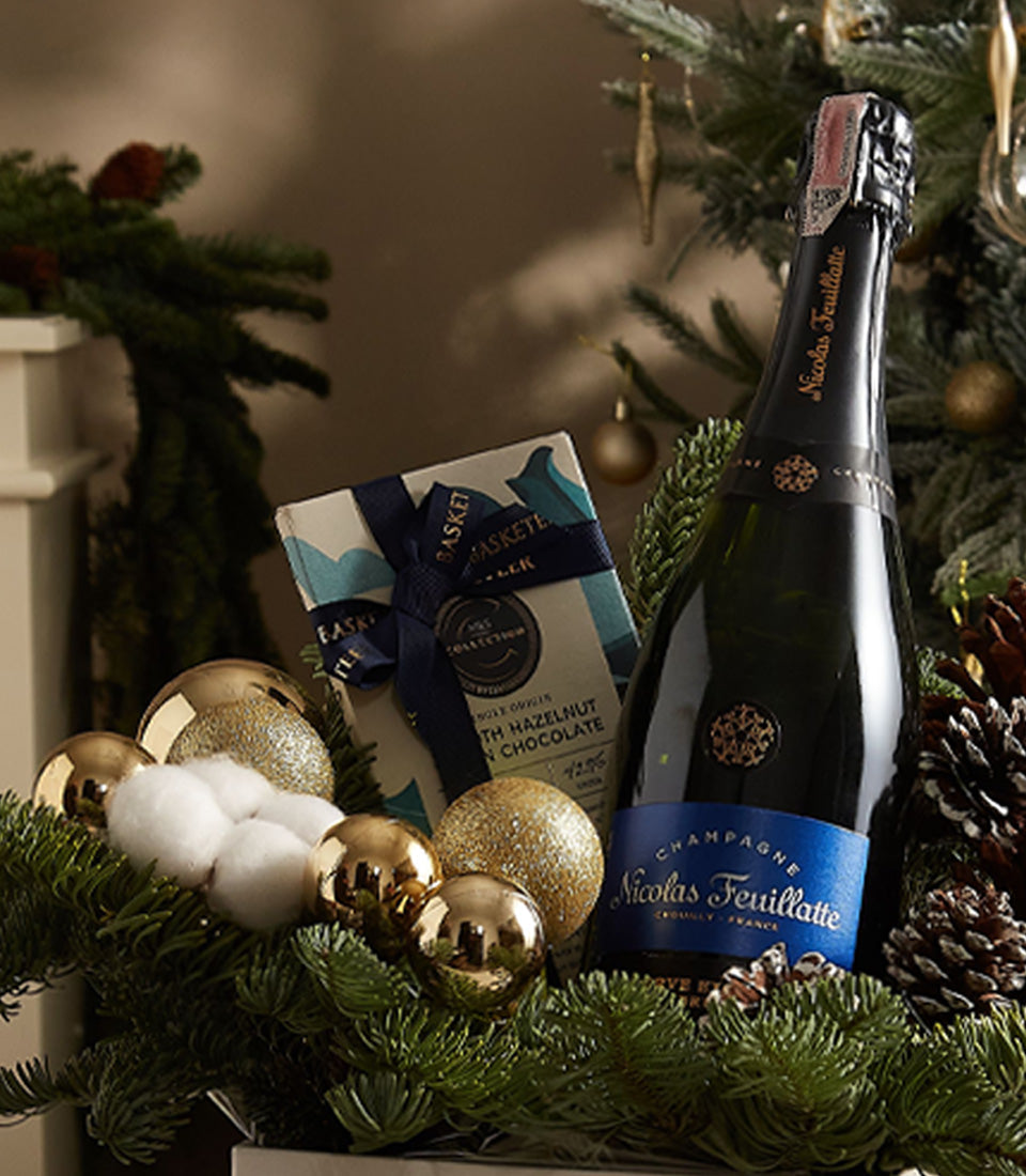Elegant blue sparkle gift box with Nicolas Feuillatte champagne, artisan chocolates, and festive gold ornaments