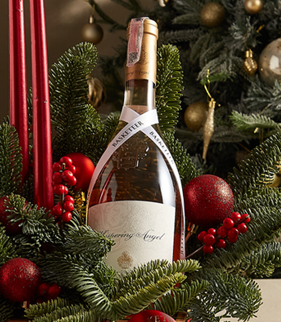 Holiday Grace wine gift set with Whispering Angel bottle, gold foil, red baubles, and pine branches