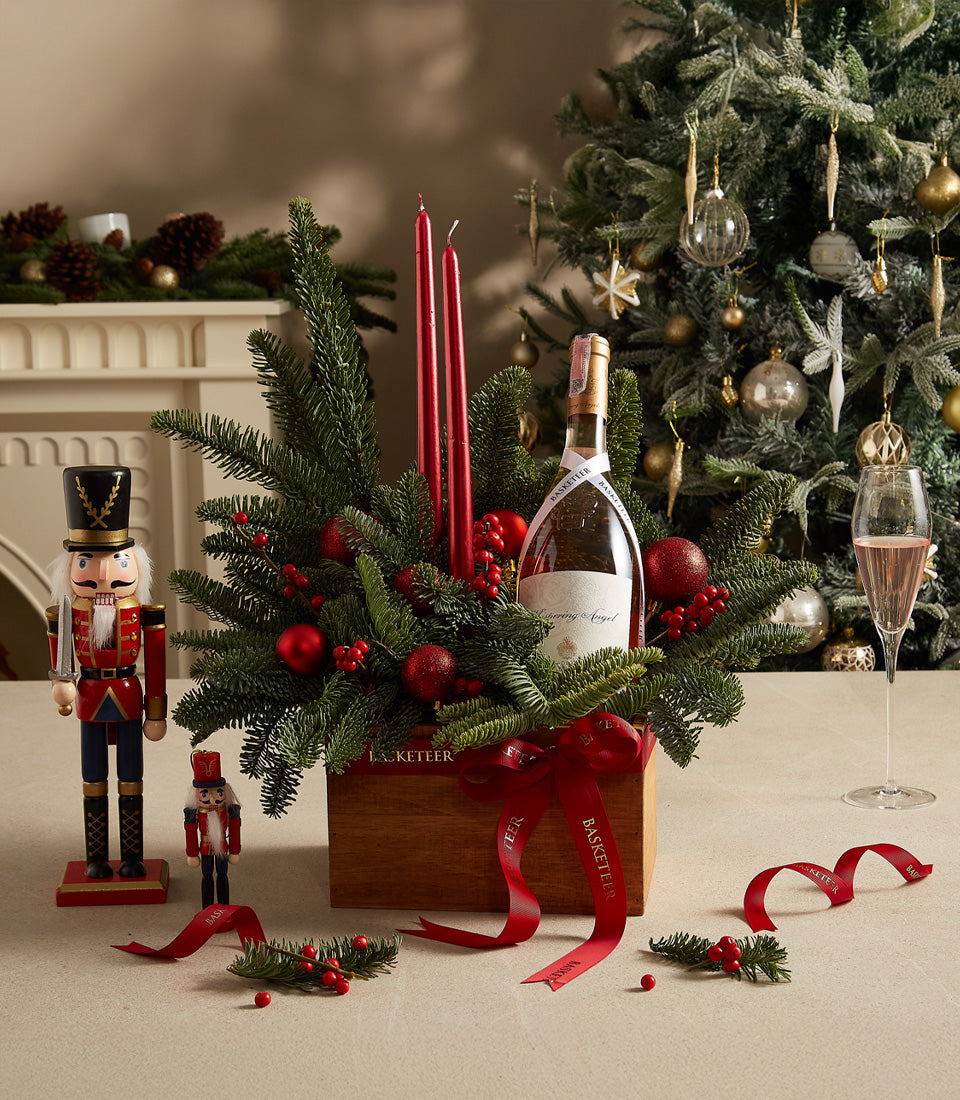 Festive wooden gift box with champagne, red candles, fresh pine, and red berries for Christmas wine gifting