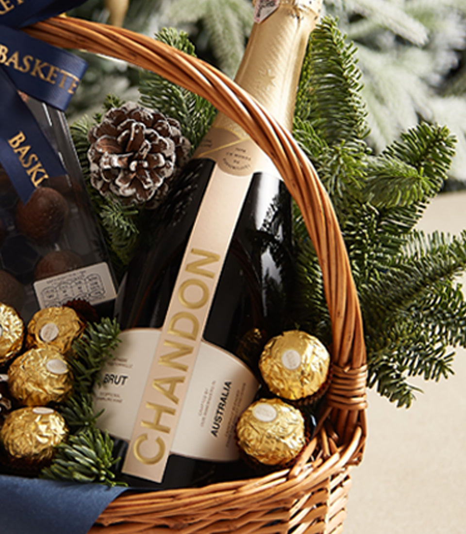 Festive gift basket with Chandon sparkling wine, luxury dark chocolates, and gold truffles in woven wicker