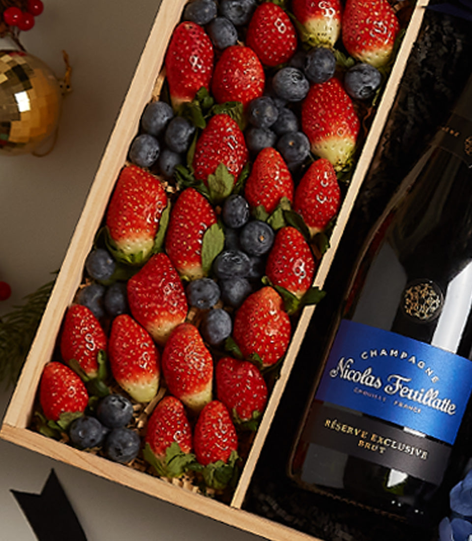 Luxury champagne and fresh berry gift box with strawberries, blueberries, and gold-accented bottle for Christmas