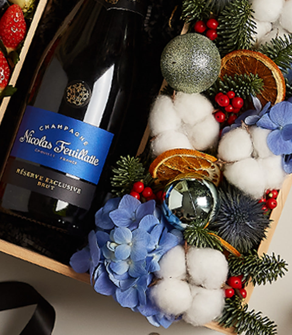 Luxury champagne gift box with Nicolas Feuillatte Brut, blue hydrangeas, berries, and festive ornaments