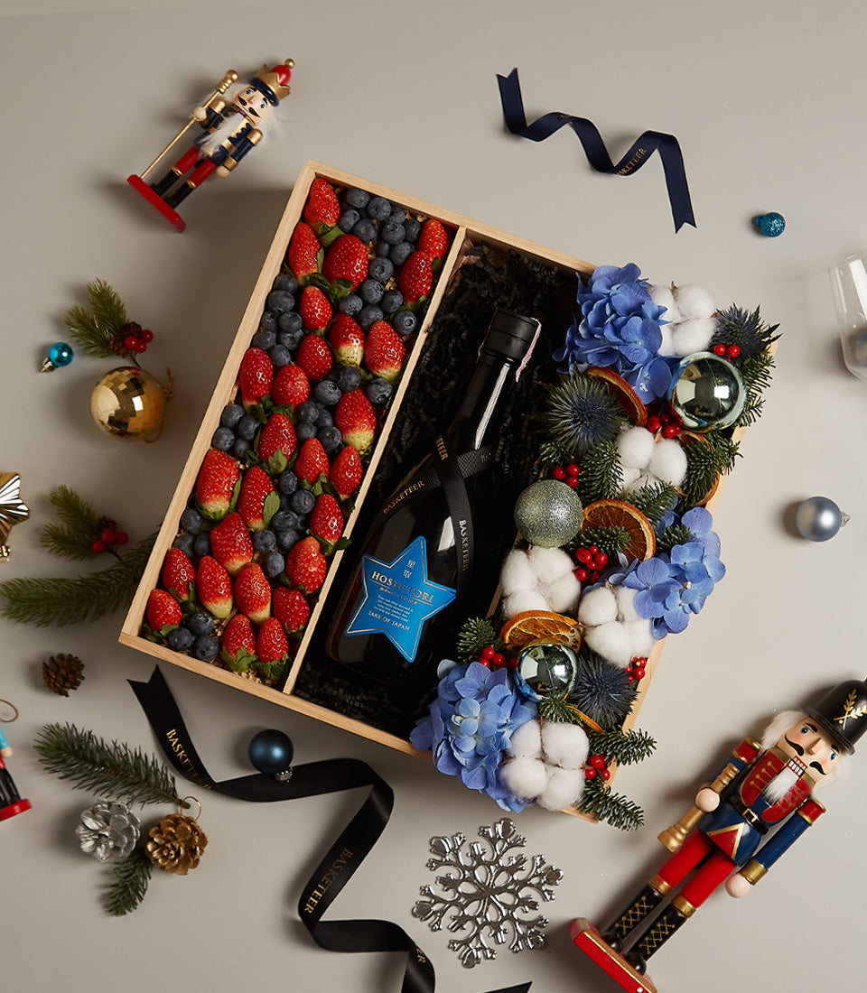 Festive wooden gift box with fresh berries, red wine, and blue hydrangea floral arrangement for Christmas