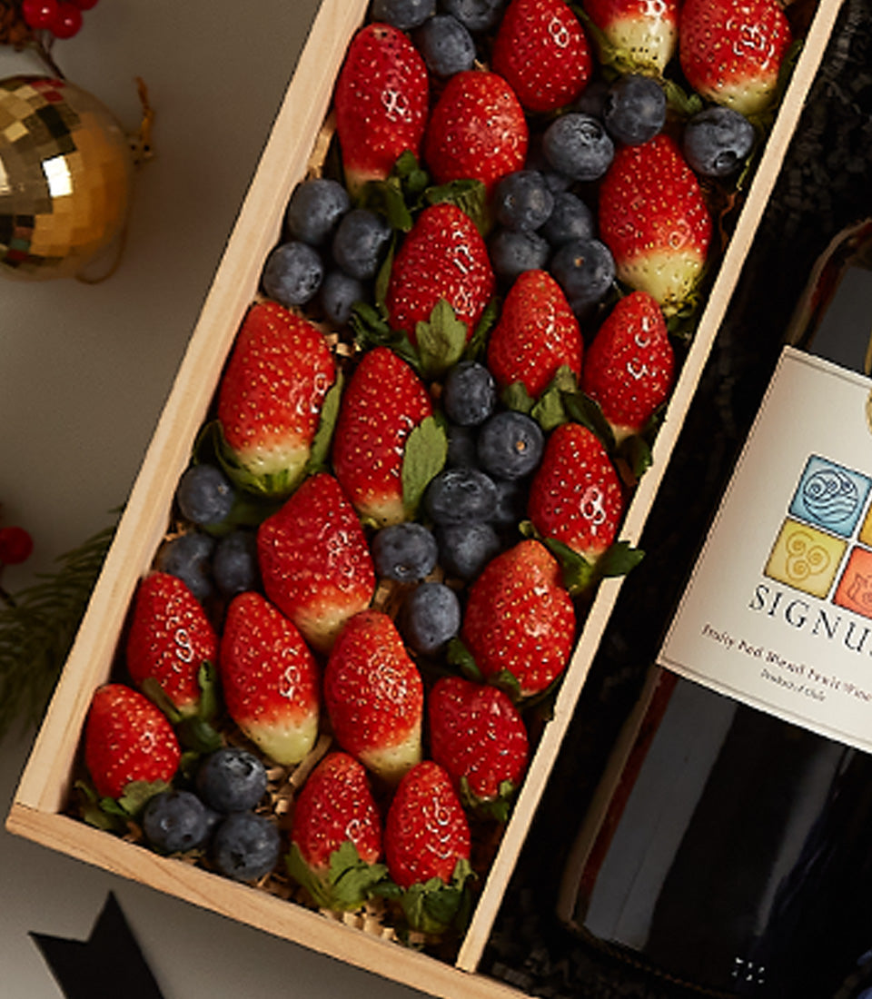 Elegant wooden gift box with fresh strawberries and blueberries, paired with red wine for Christmas