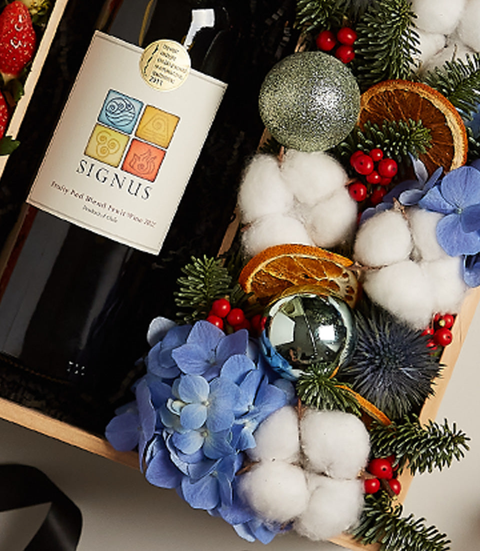 Luxury red wine gift box with hydrangea, berries, and festive ornaments in wooden crate
