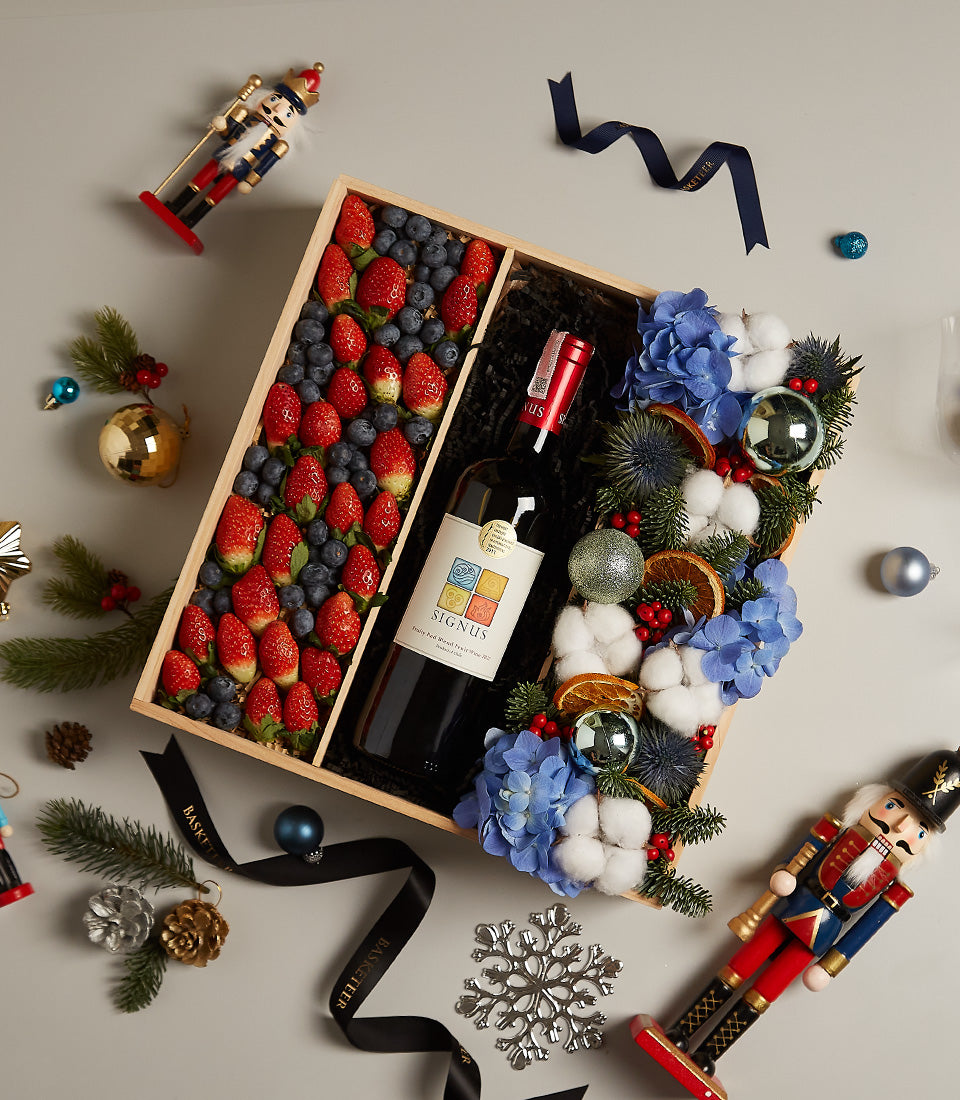 Elegant wooden gift box with red wine, fresh berries, and blue hydrangeas for Christmas