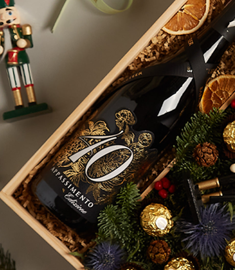 Golden Charm luxury wine gift box with Appassimento red wine, gold chocolates, pinecones, and festive nutcracker decoration