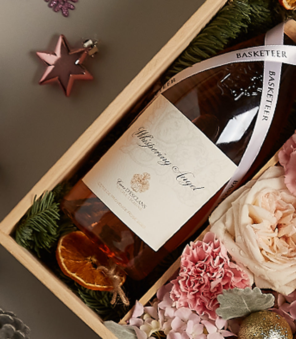 Premium rosé wine with pink roses and festive flowers in luxury gift box for Christmas