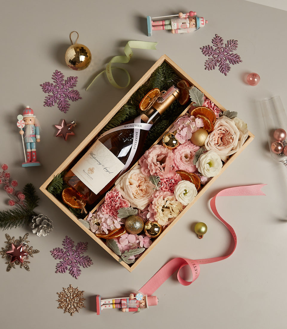 Luxury wooden wine gift box with Whispering Angel rosé, fresh pink and cream flowers, dried orange slices, and gold baubles