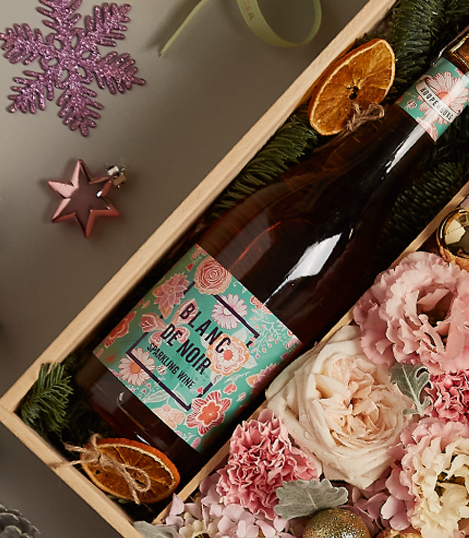 Rosy Celebration floral gift box with sparkling wine, pink roses, and festive holiday ornaments