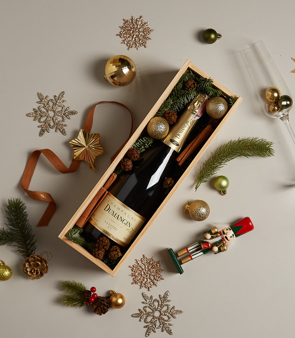 Premium Champagne Dumangin gift box with green pine branches, cinnamon sticks, and gold baubles for Christmas celebrations