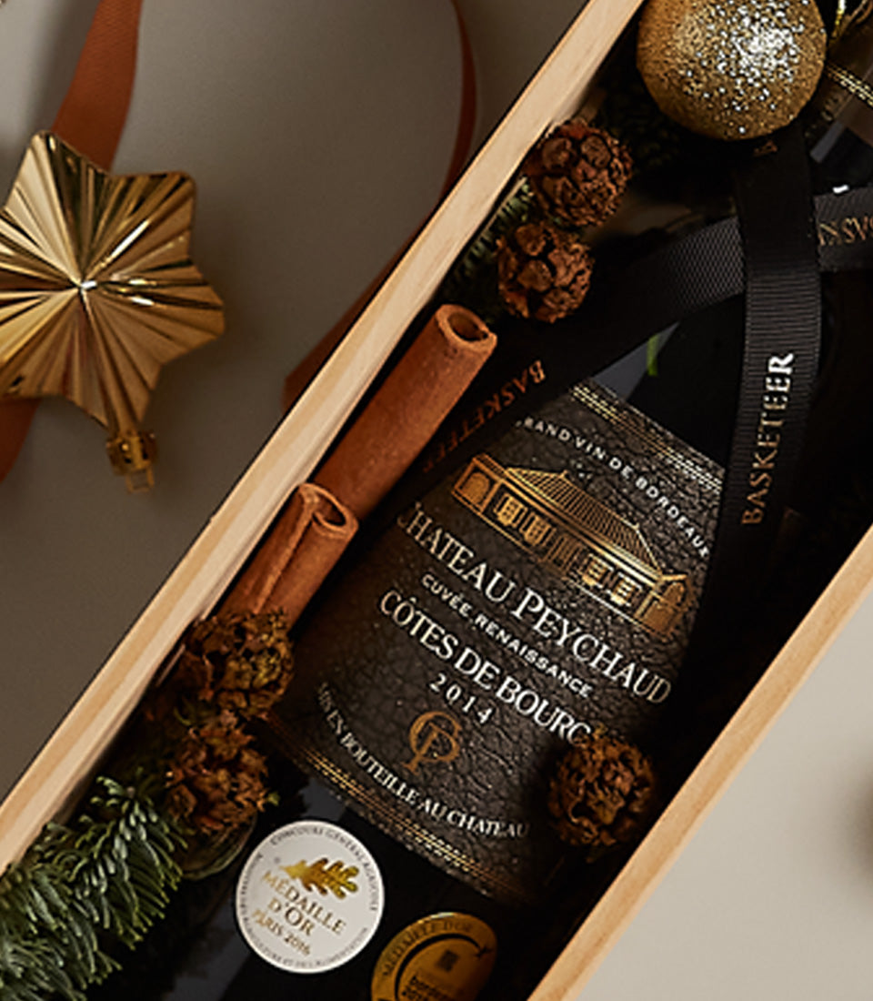Premium red wine gift box with Château Peychaud, cinnamon, pinecones, and festive gold ornaments