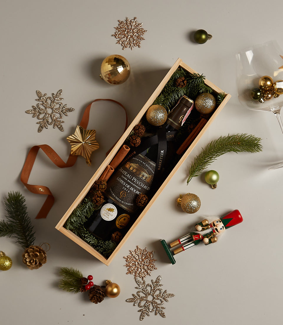 Premium red wine gift box with pine branches, cinnamon sticks, and gold ornaments for Christmas