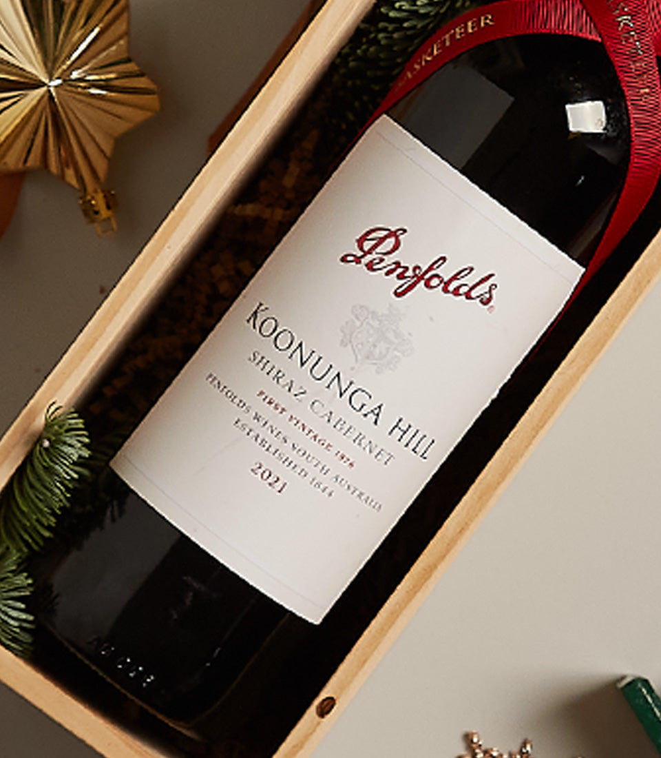 Penfolds Shiraz Cabernet red wine in wooden gift box with festive red ribbon and pine, perfect for Christmas