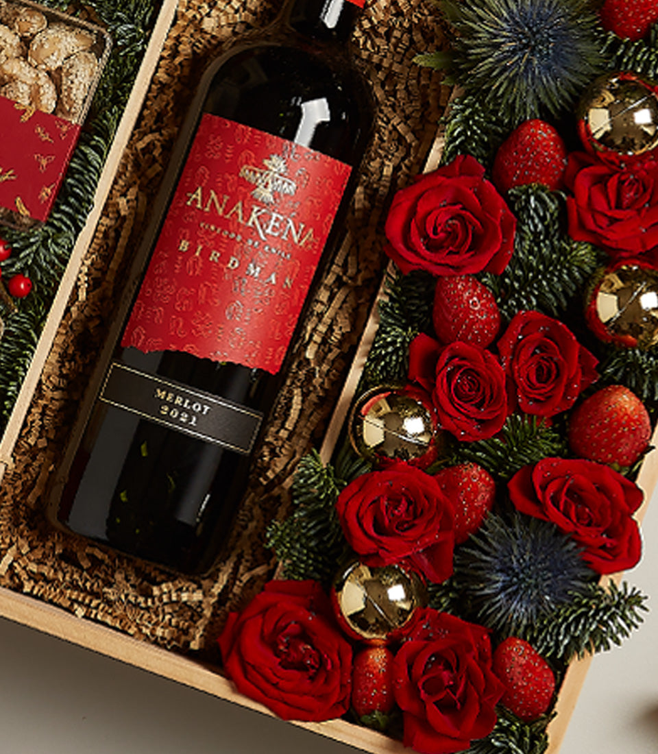 Red wine merlot hamper with red roses, strawberries, nuts and festive baubles in wooden gift box