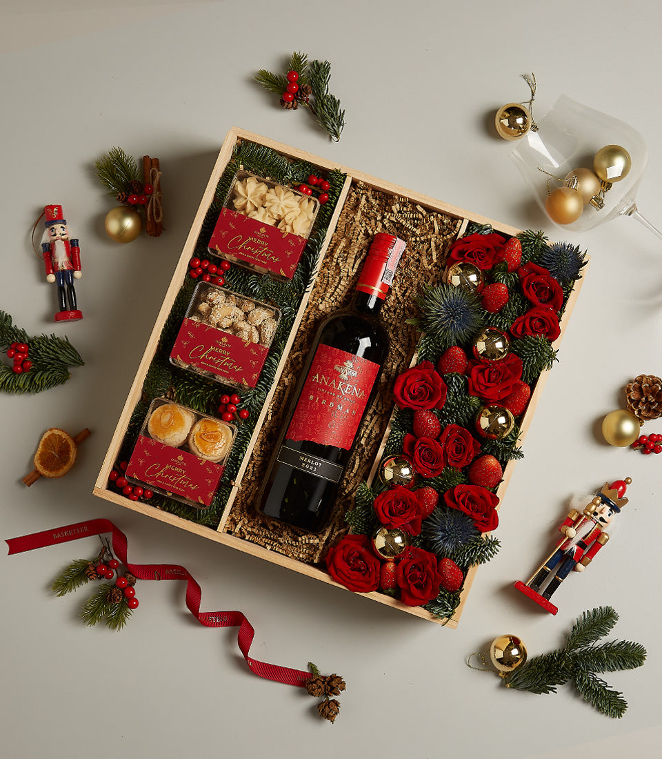 Premium red wine hamper with fresh red roses, pastries, and festive gold accents for Christmas gifting