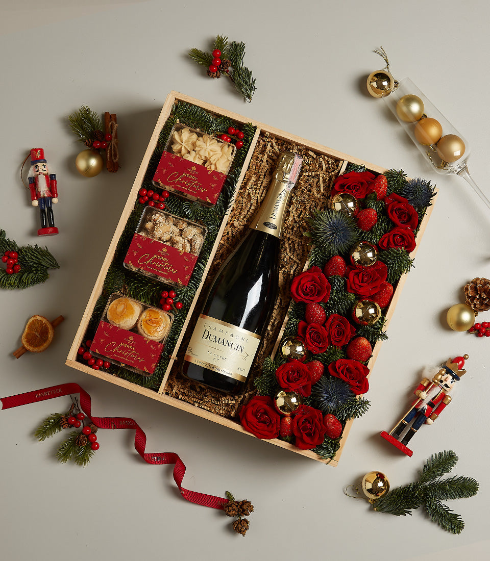 Golden wooden Christmas gift box with champagne, star cookies, nuts, pastries, red roses, and festive ornaments