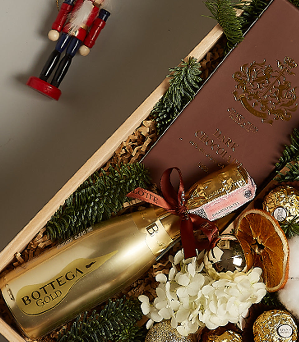 Golden Elegance festive gift box with Bottega Gold prosecco, dark chocolate, gold truffles, and pine sprigs in wooden crate
