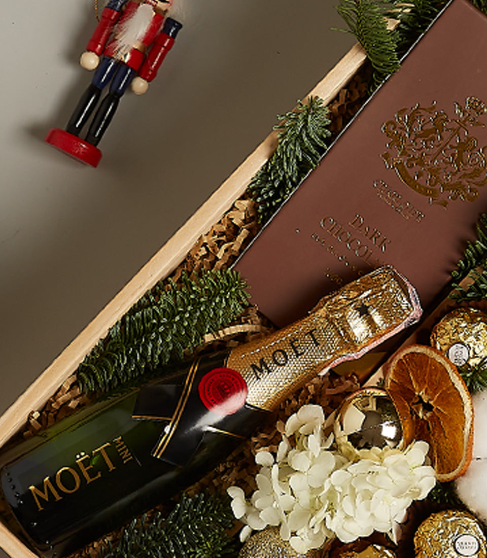 Luxury Christmas gift box with Moët champagne, dark chocolate, Ferrero Rocher, and festive gold accents