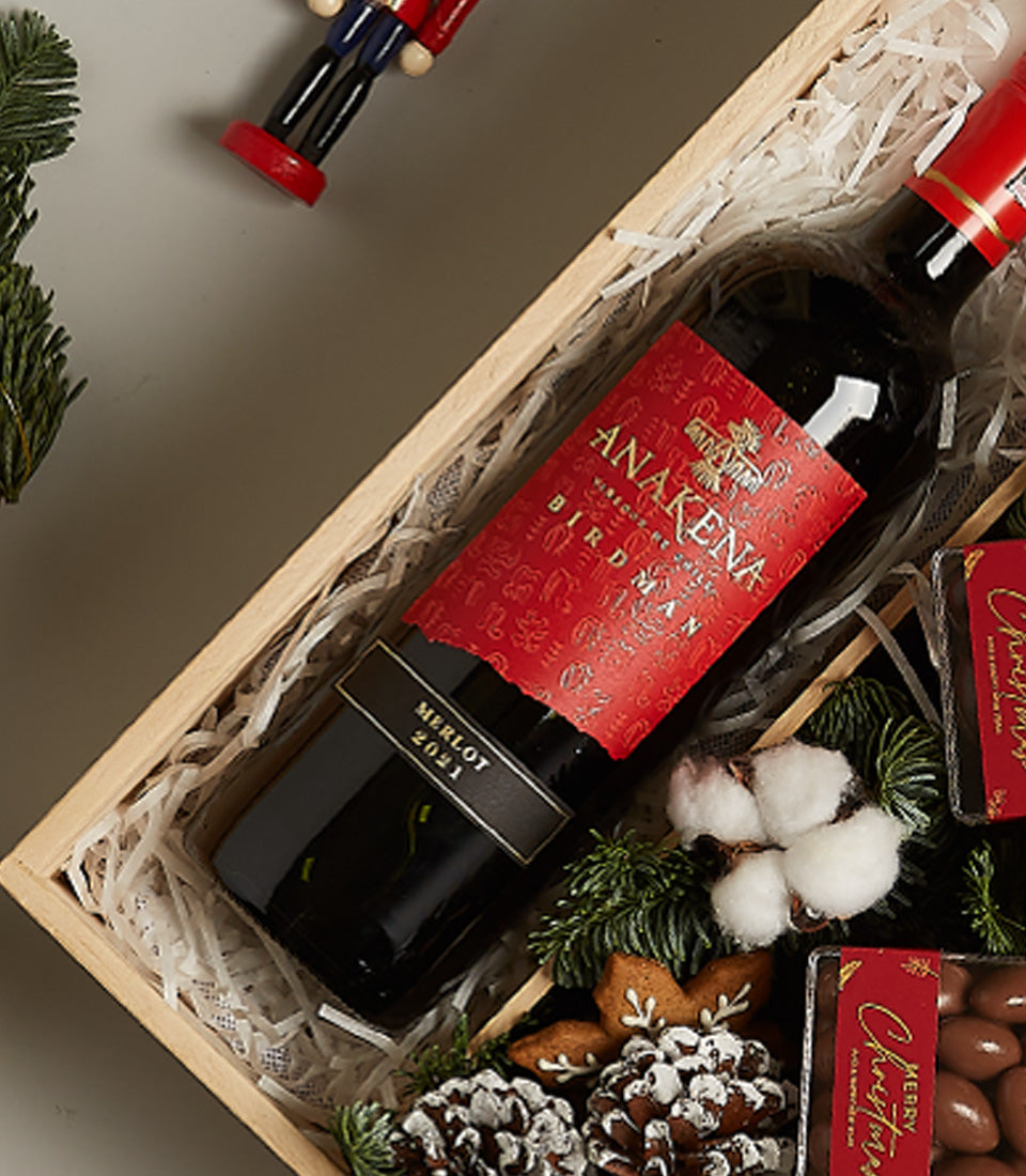 Festive red wine Christmas gift box with Merlot, gingerbread cookies, chocolate treats, and holiday décor