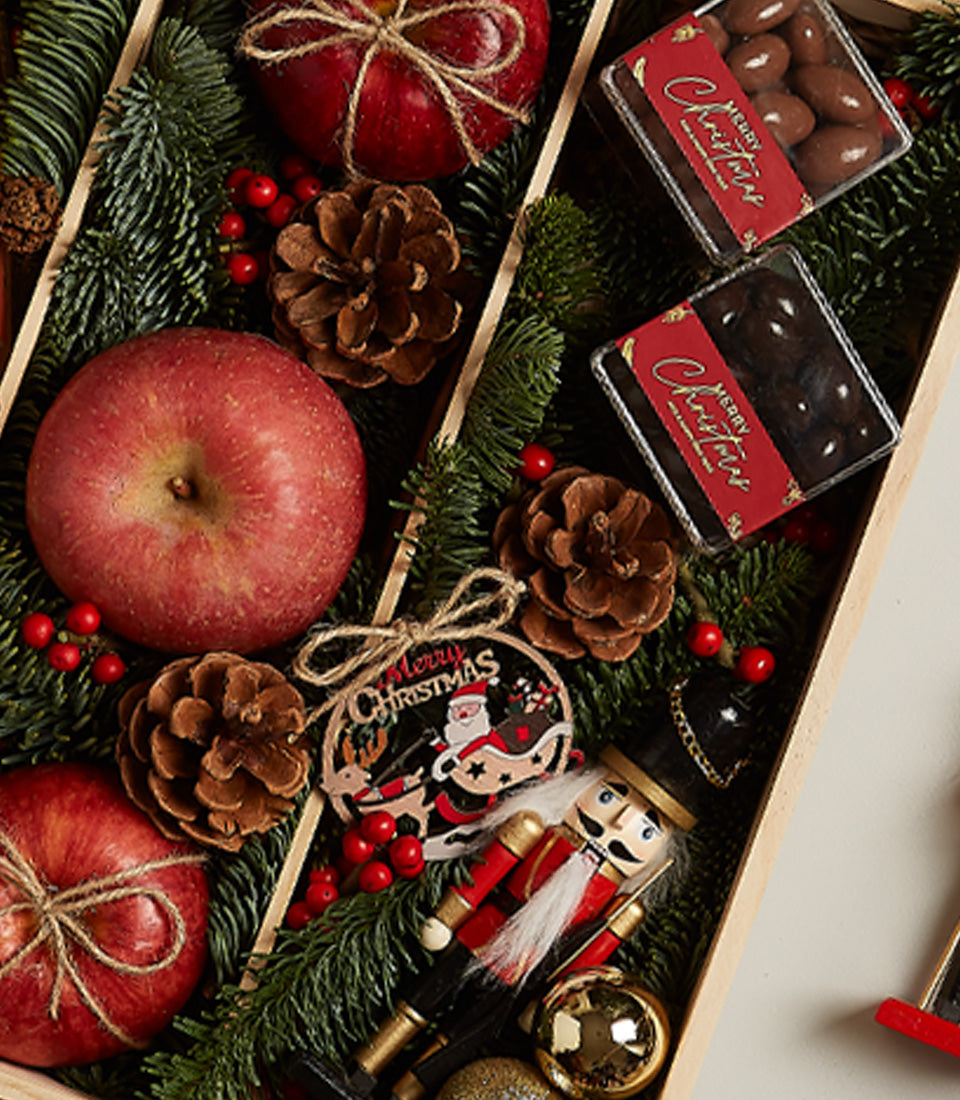 Rosé Elegance Christmas gift box with champagne, chocolate almonds, apples, and festive wooden ornaments