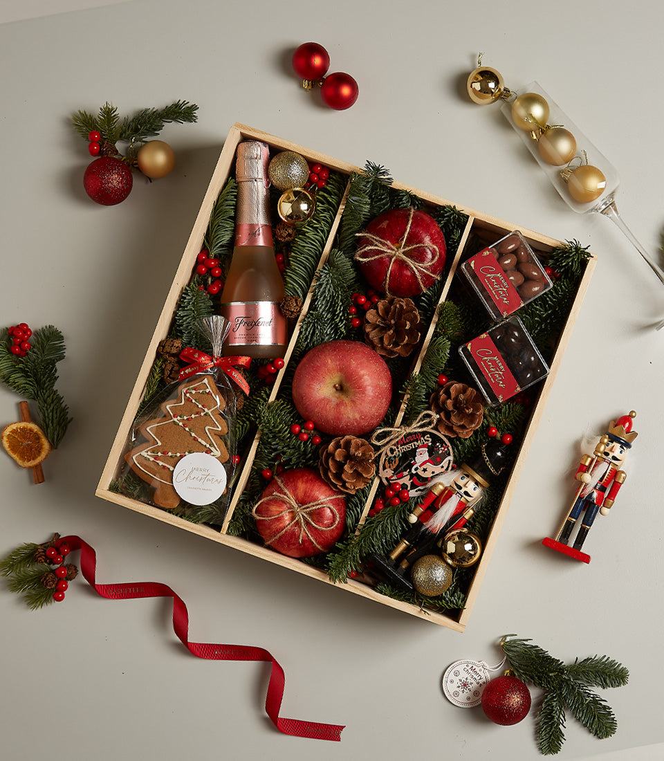 Rosé sparkling wine Christmas gift box with gourmet chocolates, apples, and festive ornaments