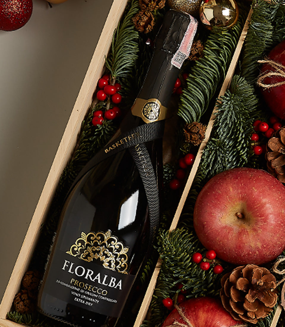 Holiday Luxe prosecco gift set with green pine, red berries, apples, and pinecones in wooden box