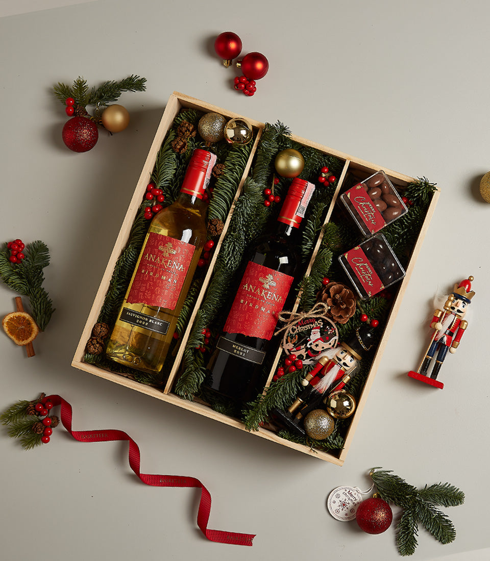 Festive wine pair gift box with red and white wine, chocolates, and holiday decorations in divided wooden box