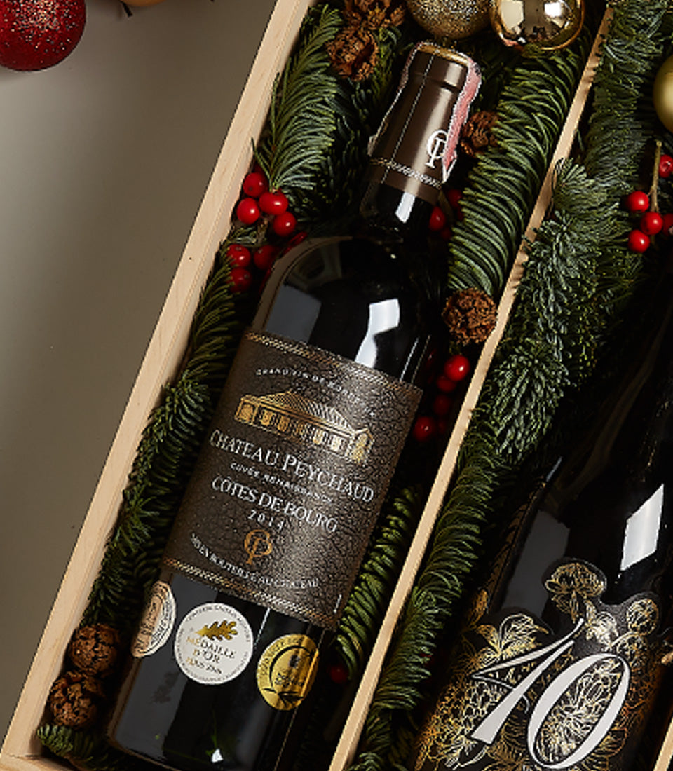 Elegant wine gift box with Château Peychaud red wine and holiday decorations in dark wooden presentation box