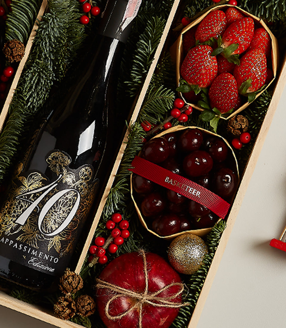 Elegant red wine with fresh strawberries, cherries, and festive pine branch arrangement Christmas hamper