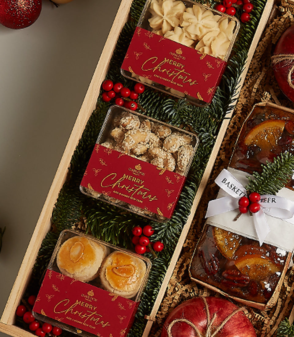Festive gourmet hamper with star cookies, fruitcakes, nuts and fresh apple in wooden crate